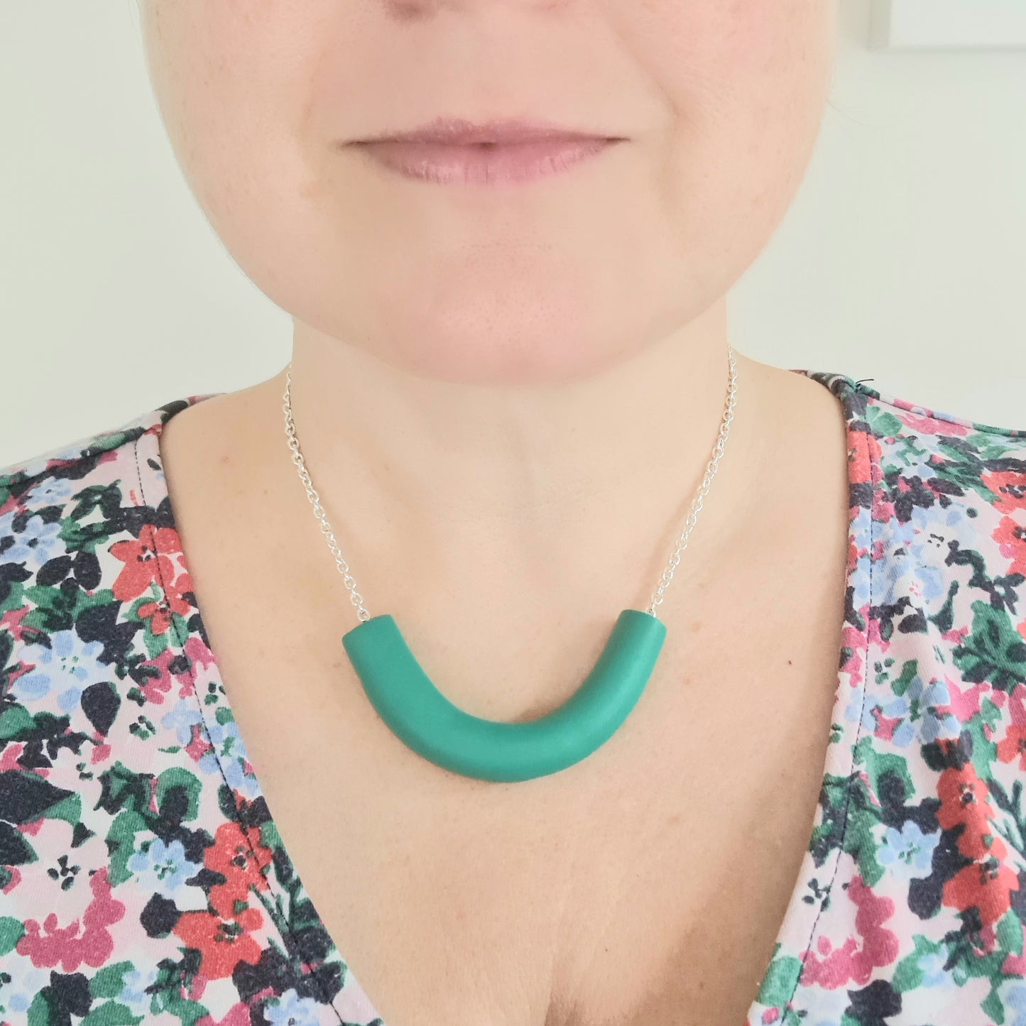 A close up of Amy wearing a chunky green necklace that has been handmade from polymer clay.