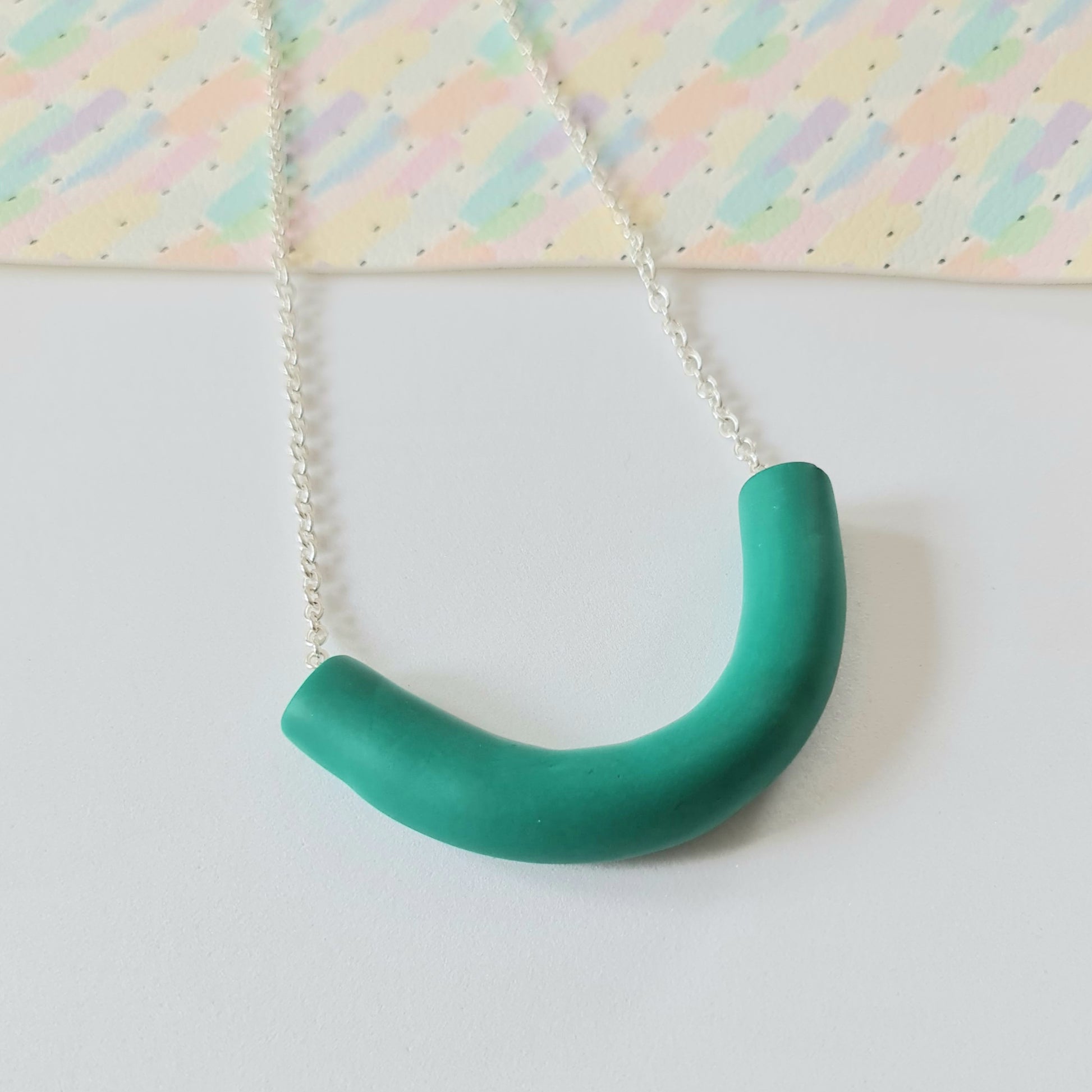 A women's chunky green necklace on a silver coloured chain on a white background.