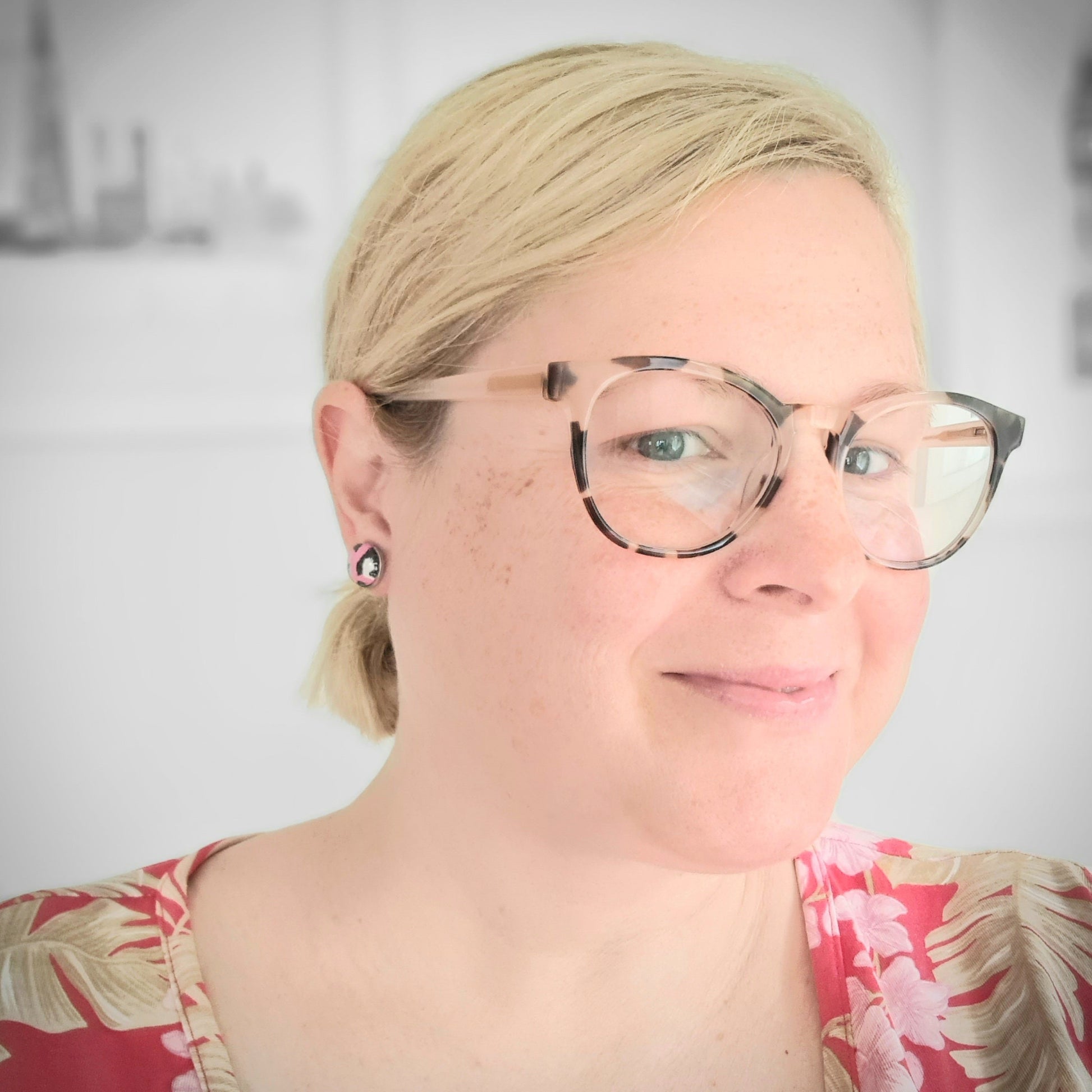 A picture of Amy Ayton wearing a pair of pink leopard print stud earrings.